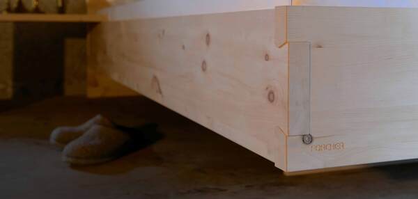 Massives Holzbett mit sichtbarer Eckverbindung, hochwertiger Verarbeitung und Holzstruktur.