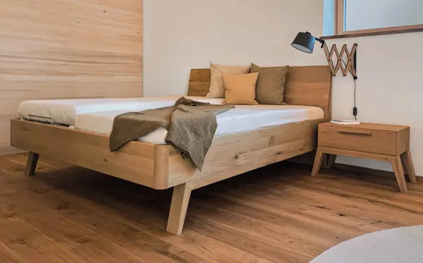 Modernes Schlafzimmer mit Massivholzbett, Nachttisch und stilvoller Beleuchtung.